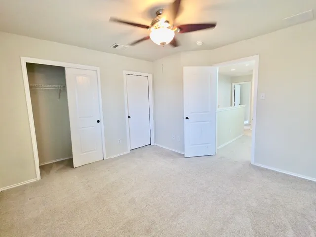 an empty room with closet and a ceiling fan