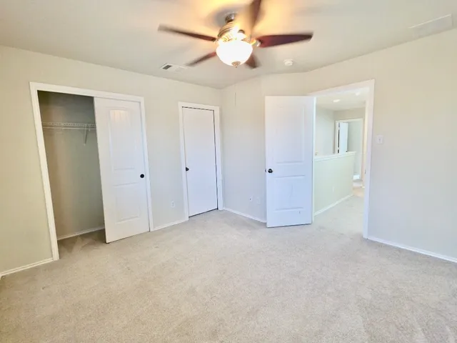 an empty room with closet and a ceiling fan