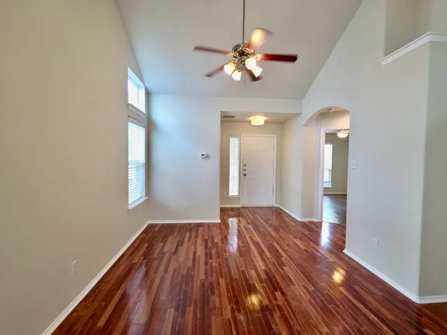 a view of empty room with wooden floor and fan