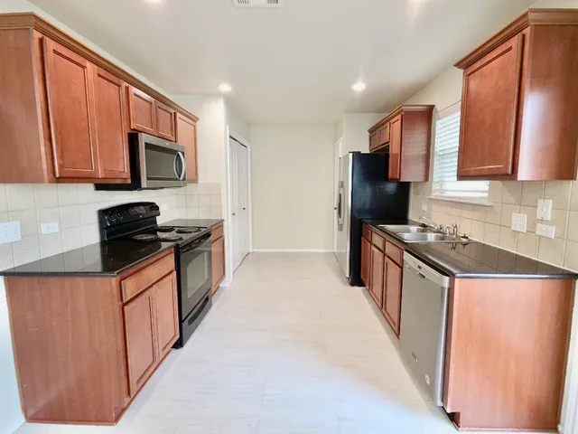 a kitchen with stainless steel appliances granite countertop a refrigerator a stove top oven a sink and dishwasher