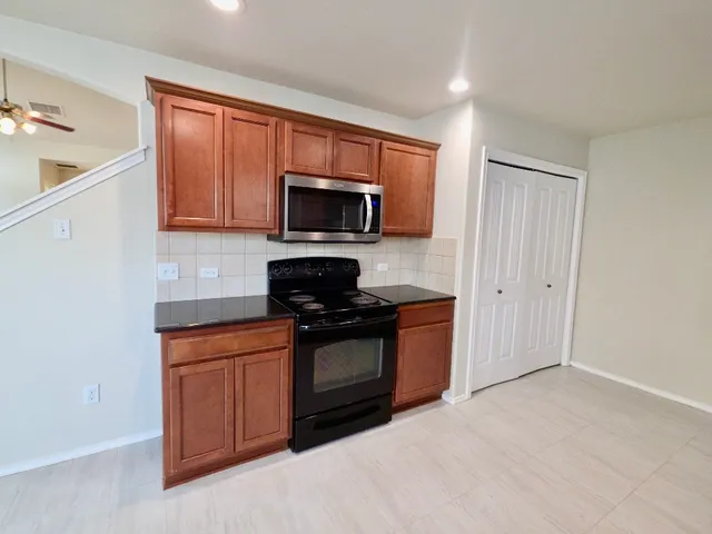 a kitchen with stainless steel appliances granite countertop a stove a sink and a microwave