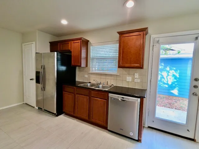 a kitchen with stainless steel appliances granite countertop a refrigerator and a sink
