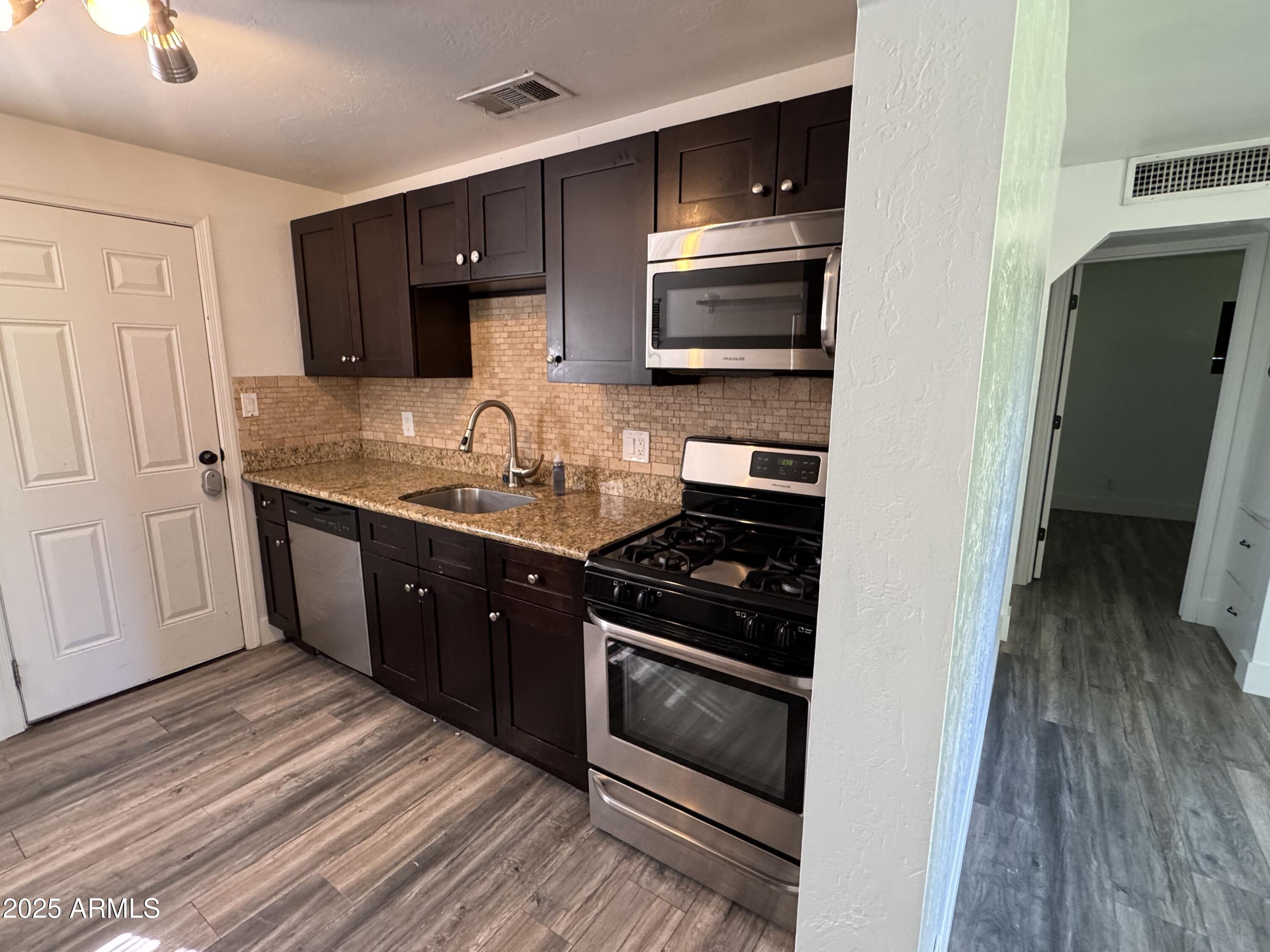 3134 North 28th Street Phoenix, AZ 85016 - Photo 15 of 21 a kitchen with stainless steel appliances granite countertop a stove a sink and a microwave