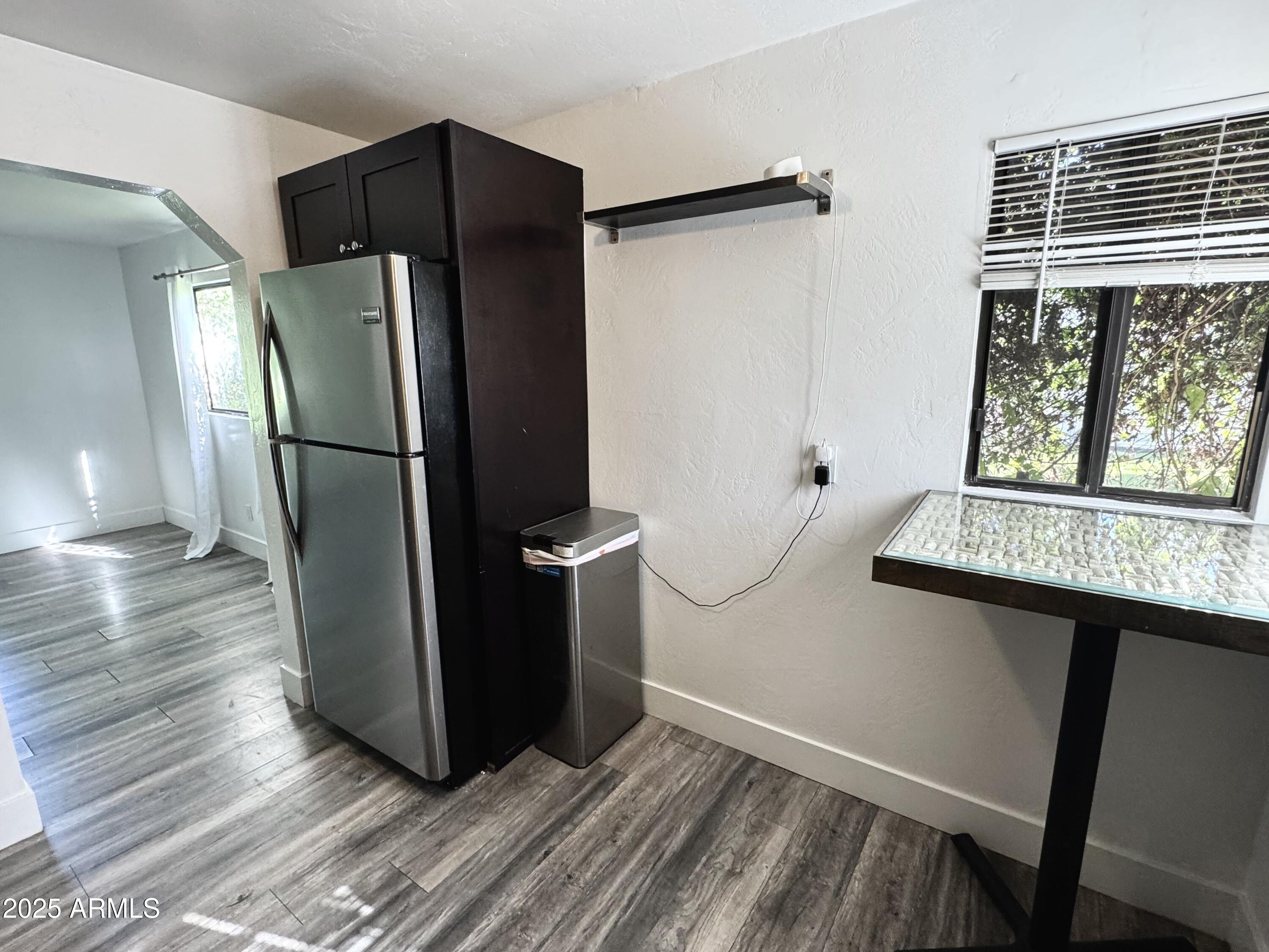 3134 North 28th Street Phoenix, AZ 85016 - Photo 16 of 21 a view of a refrigerator in kitchen and an empty room with wooden floor