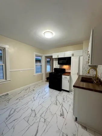 a large kitchen with granite countertop a sink and white cabinets