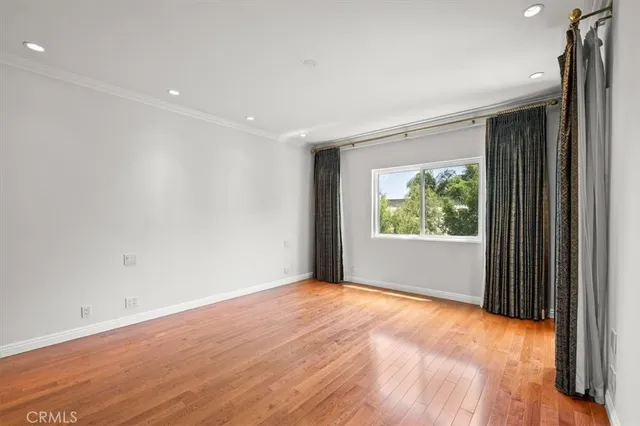 a view of an empty room with wooden floor and a bathroom