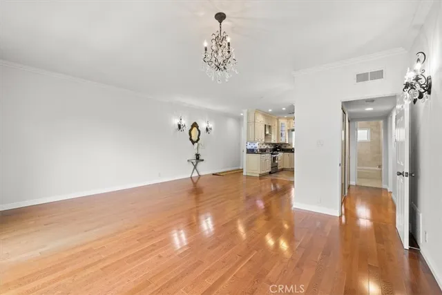 a view of a livingroom with wooden floor and a kitchen