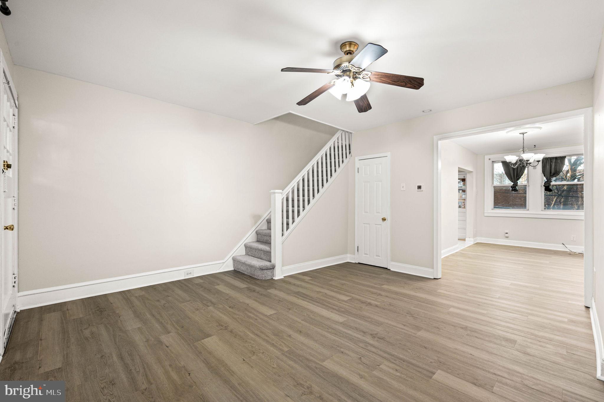 a view of an empty room with wooden floor and a ceiling fan