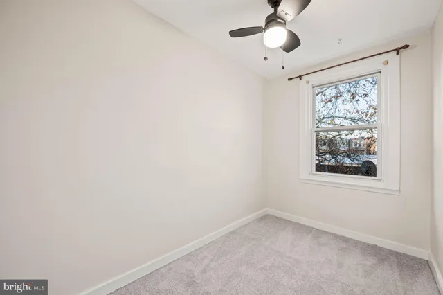 an empty room with a window and a fan