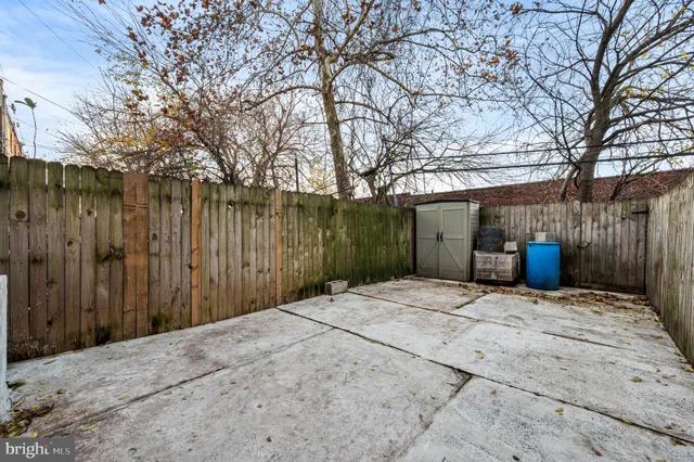 a backyard of a house with large trees and wooden fence