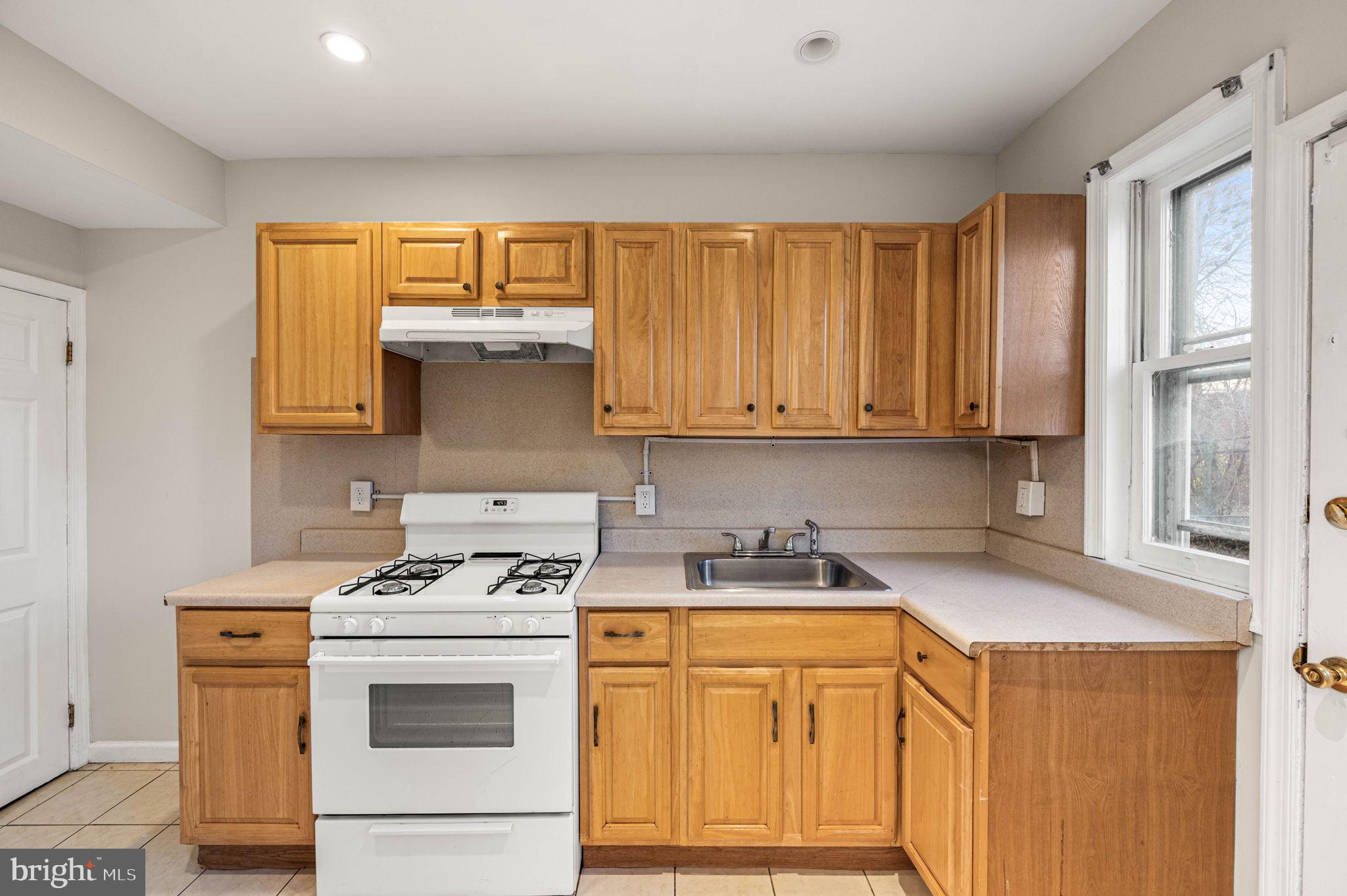 7113 Theodore Street Philadelphia, PA 19142 - Photo 10 of 26 a kitchen with stainless steel appliances a stove a sink cabinets and a window