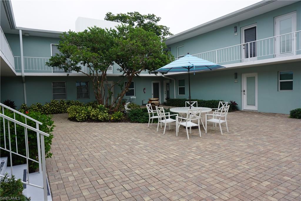 663 12th Avenue South, Unit 663 Naples, FL 34102 - Photo 2 of 14 a view of a patio with table and chairs under an umbrella