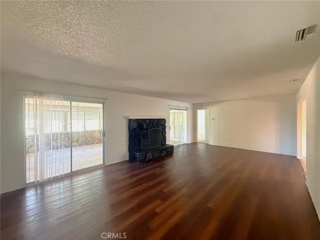 an empty room with a chandelier fan and windows
