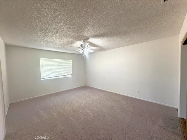 an empty room with chandelier fan and windows
