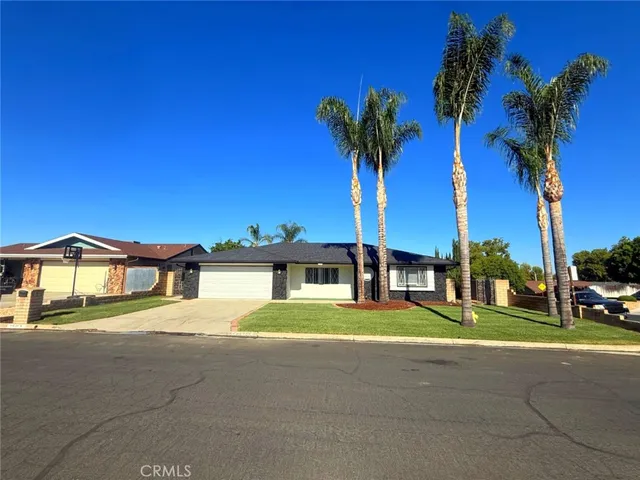 a view of a house with a yard and palm trees