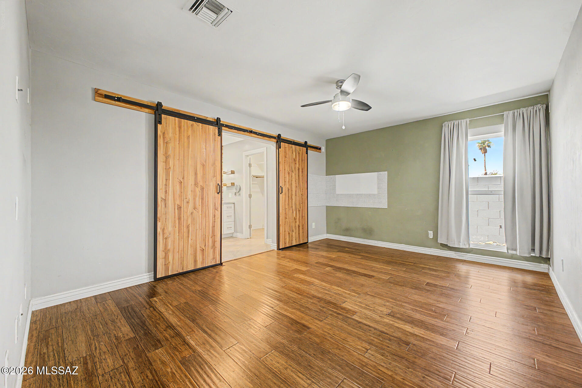 7550 East Rio Verde Drive Tucson, AZ 85715 - Photo 14 of 25 The spacious primary suite features beautiful flooring and stylish barn doors leading to the ensuite bath.
