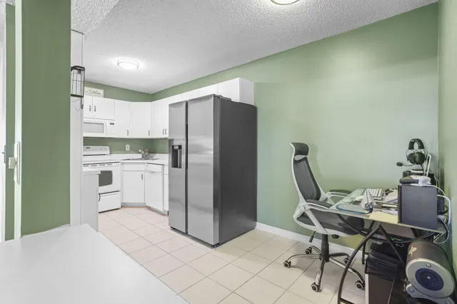 a kitchen with a refrigerator and white cabinets