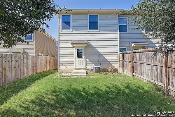 a view of a backyard with white wall and wooden fence