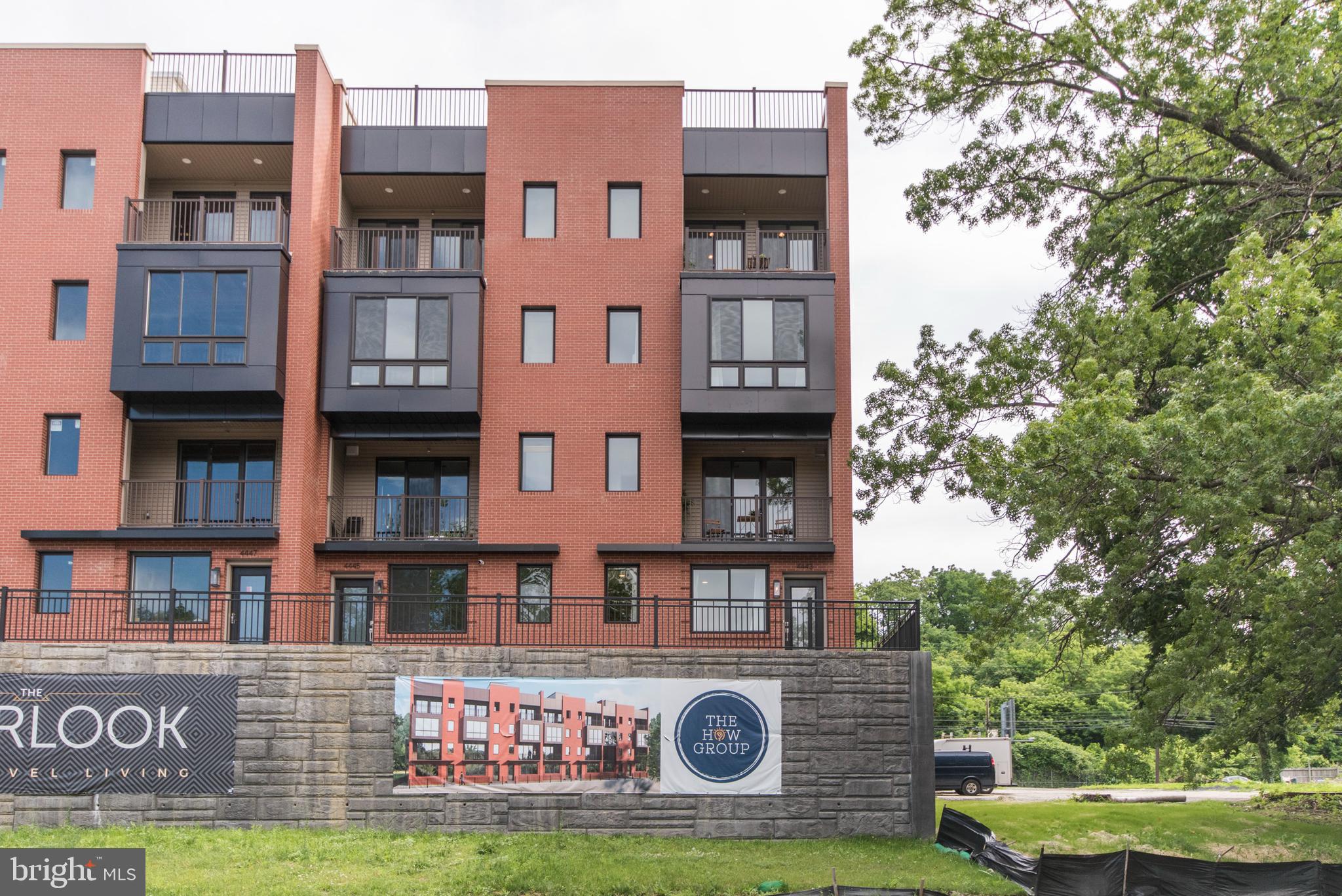 4443 River Ridge Court, Unit 13 Philadelphia, PA 19129 - Photo 1 of 35 a front view of a building with garden and tall trees