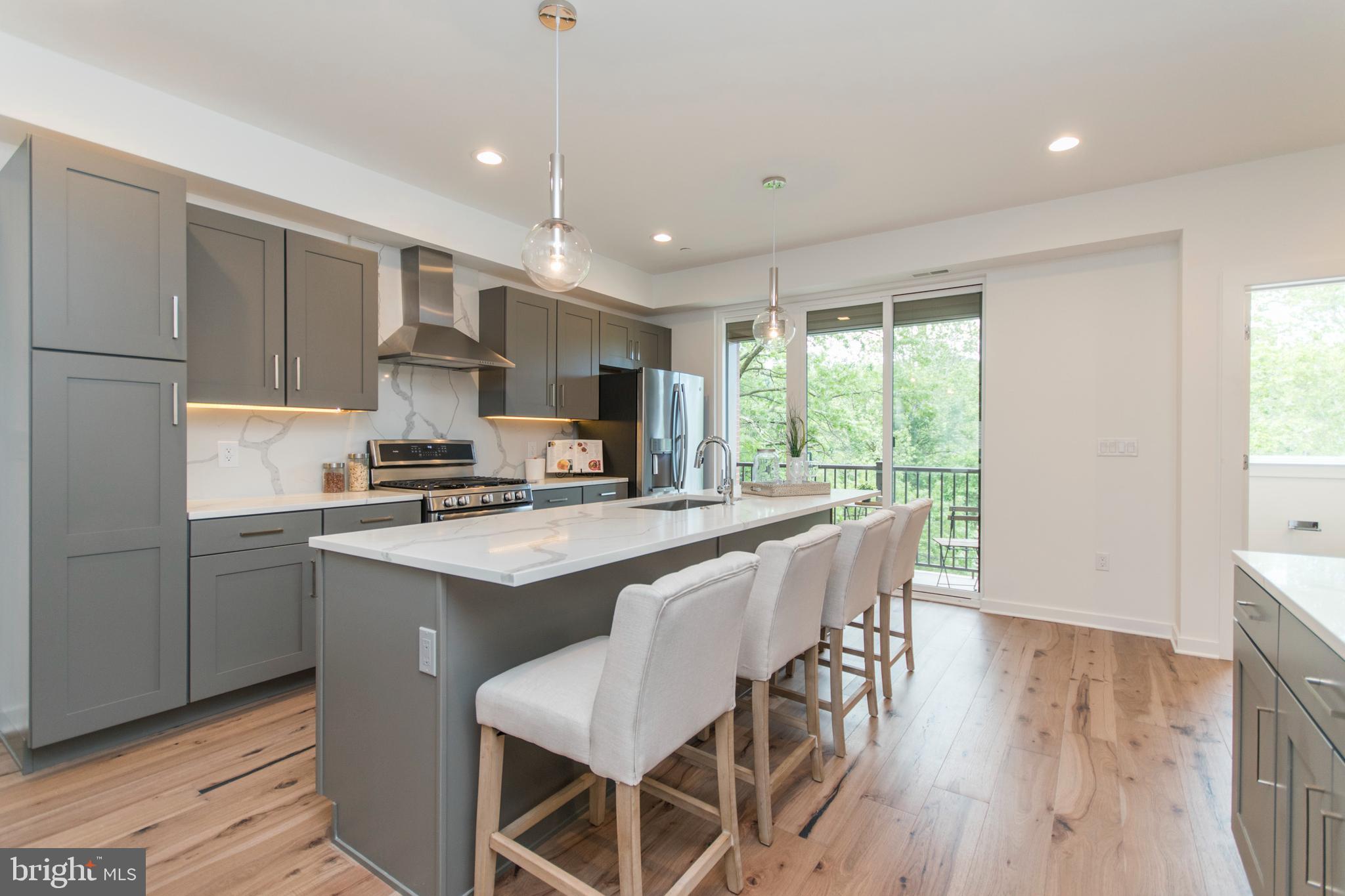 4443 River Ridge Court, Unit 13 Philadelphia, PA 19129 - Photo 4 of 35 a kitchen with stainless steel appliances granite countertop a stove a refrigerator a sink dishwasher and a dining table with wooden floor