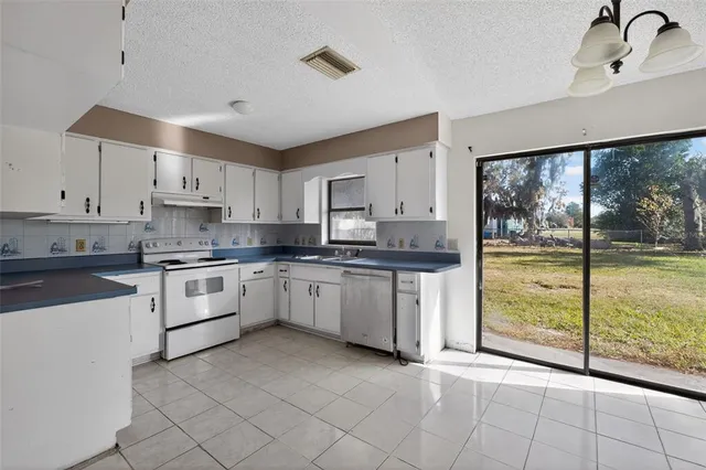 a kitchen with granite countertop a stove a sink and white cabinets