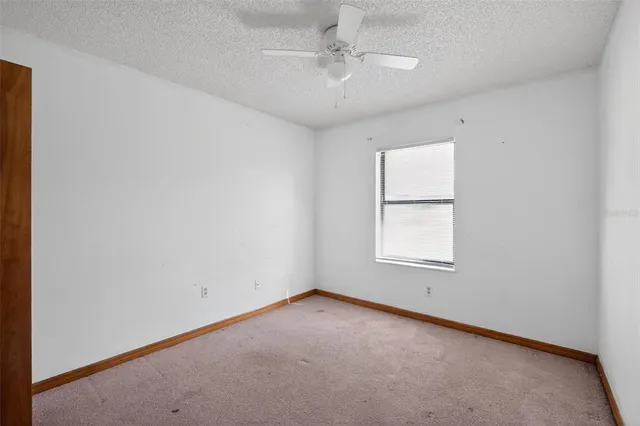 an empty room with a window and ceiling fan