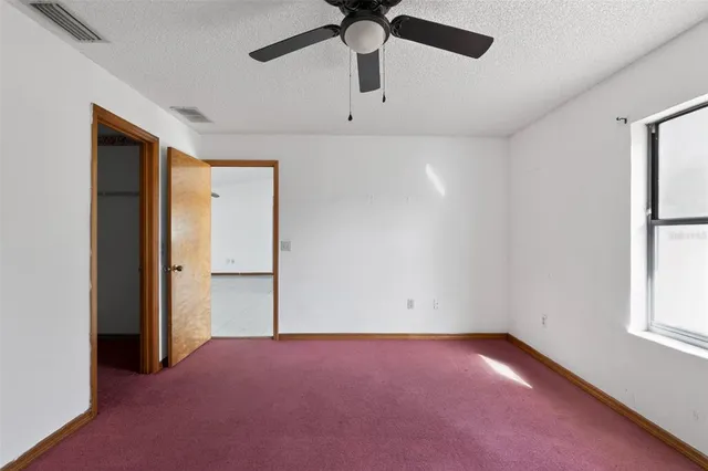 an empty room with windows and ceiling fan