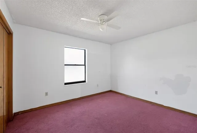 an empty room with a window and a fan