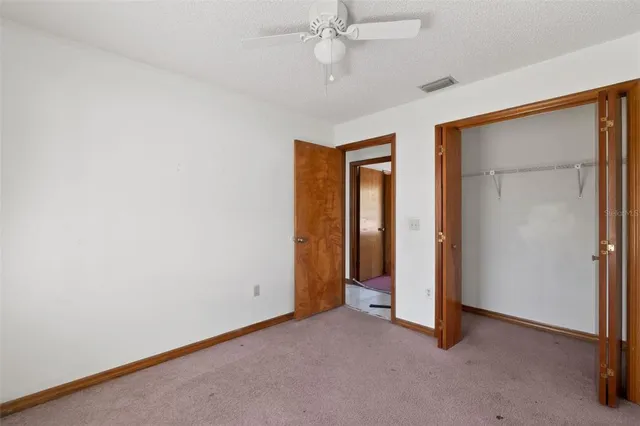 an empty room with closet and a ceiling fan