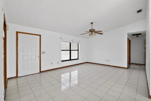 an empty room with windows and ceiling fan