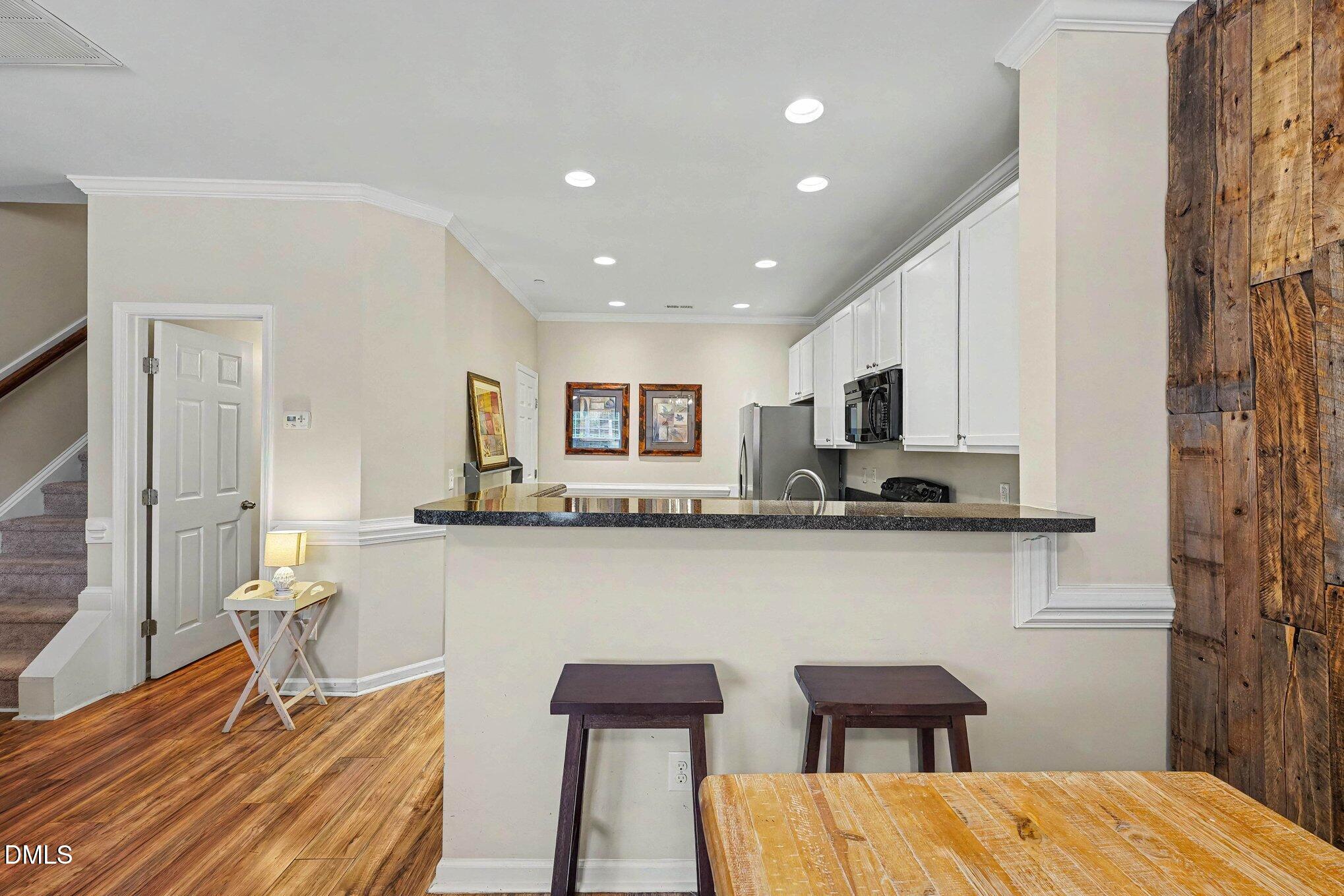 1130 Renewal Place, Unit 106 Raleigh, NC 27603 - Photo 9 of 34 a open kitchen with stainless steel appliances granite countertop a dining table chairs and a refrigerator