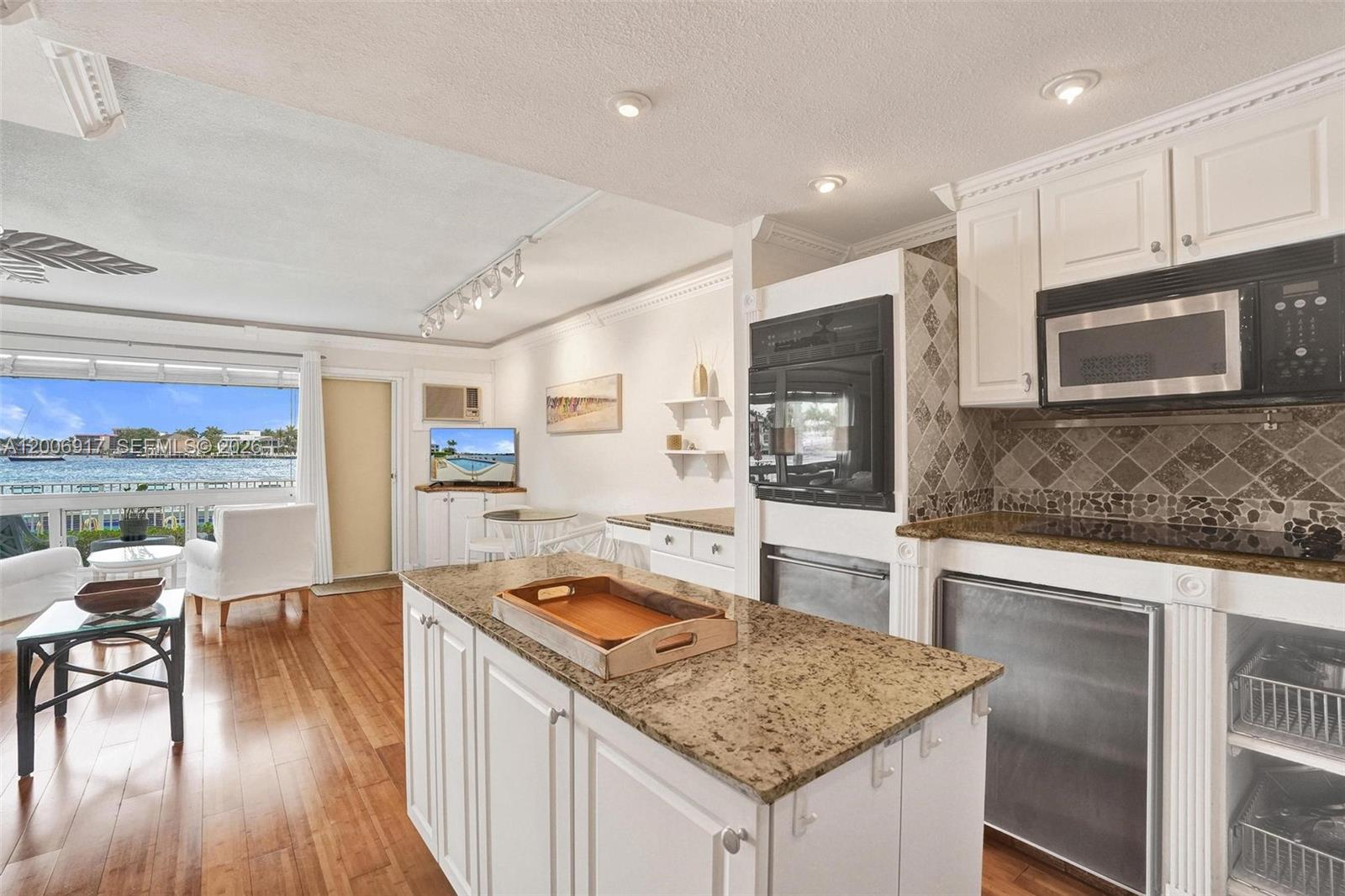 1105 South Riverside Drive, Unit 107 Pompano Beach, FL 33062 - Photo 6 of 31 a kitchen with stainless steel appliances granite countertop a stove top oven a sink dishwasher a dining table and chairs with wooden floor