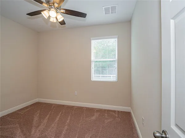 an empty room with a chandelier fan and windows