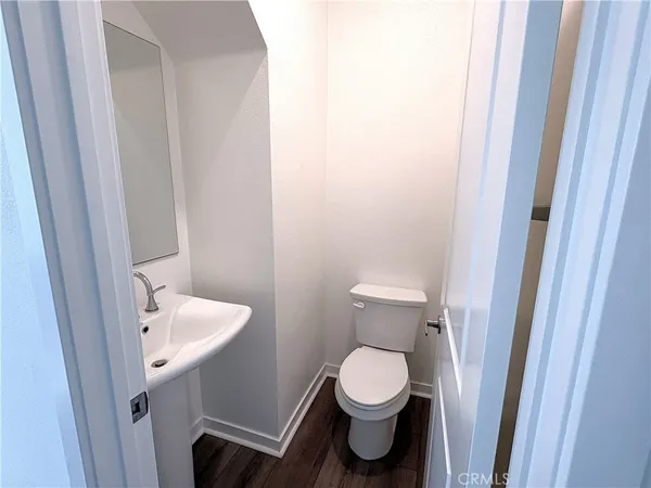 a view of a hallway with wooden floor and a bathroom