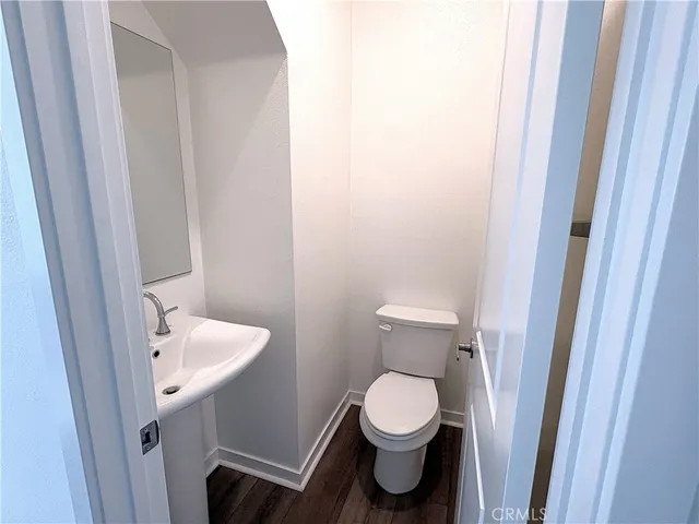 a view of a hallway with wooden floor and a bathroom