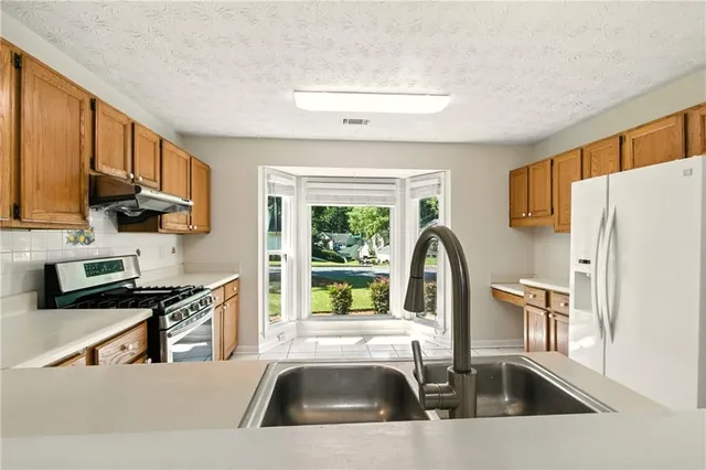 a kitchen with a sink a counter top space cabinets stainless steel appliances and a window