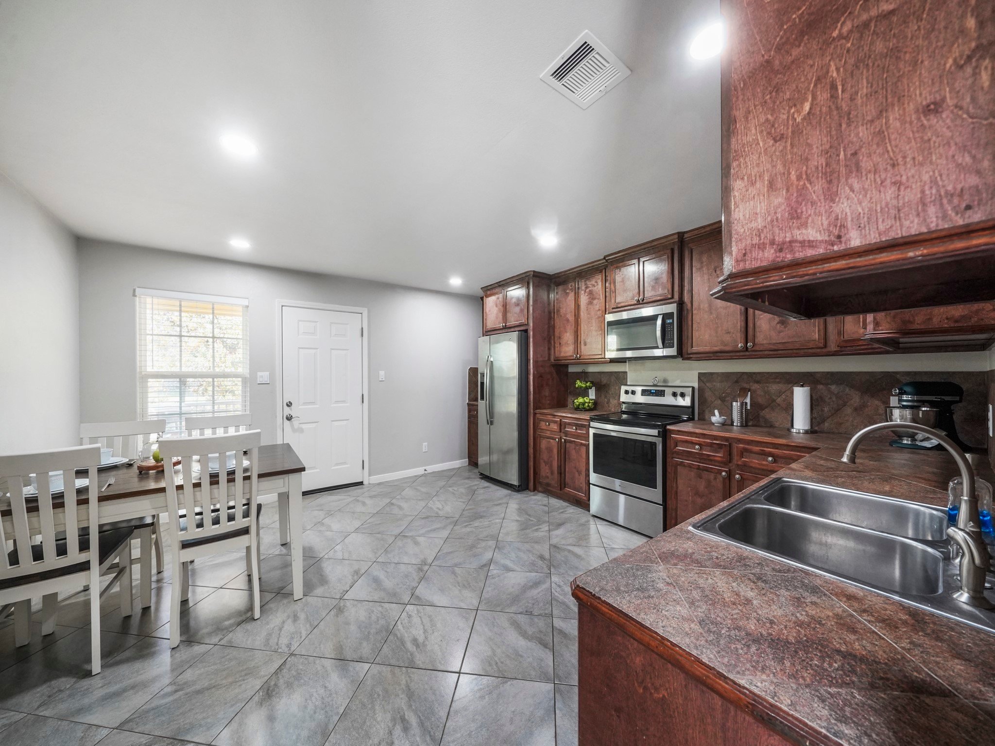 910 Rosewick Street Houston, TX 77015 - Photo 9 of 14 a kitchen with stainless steel appliances granite countertop a stove top oven a sink a dining table and chairs