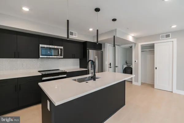 a kitchen with a sink a refrigerator a microwave a island and cabinets