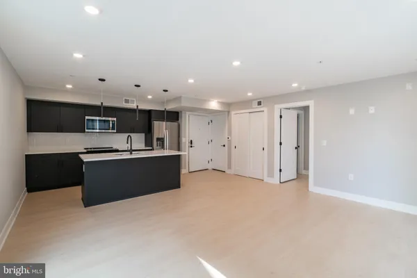 a large kitchen with stainless steel appliances kitchen island a sink dishwasher a stove and black cabinets with wooden floor