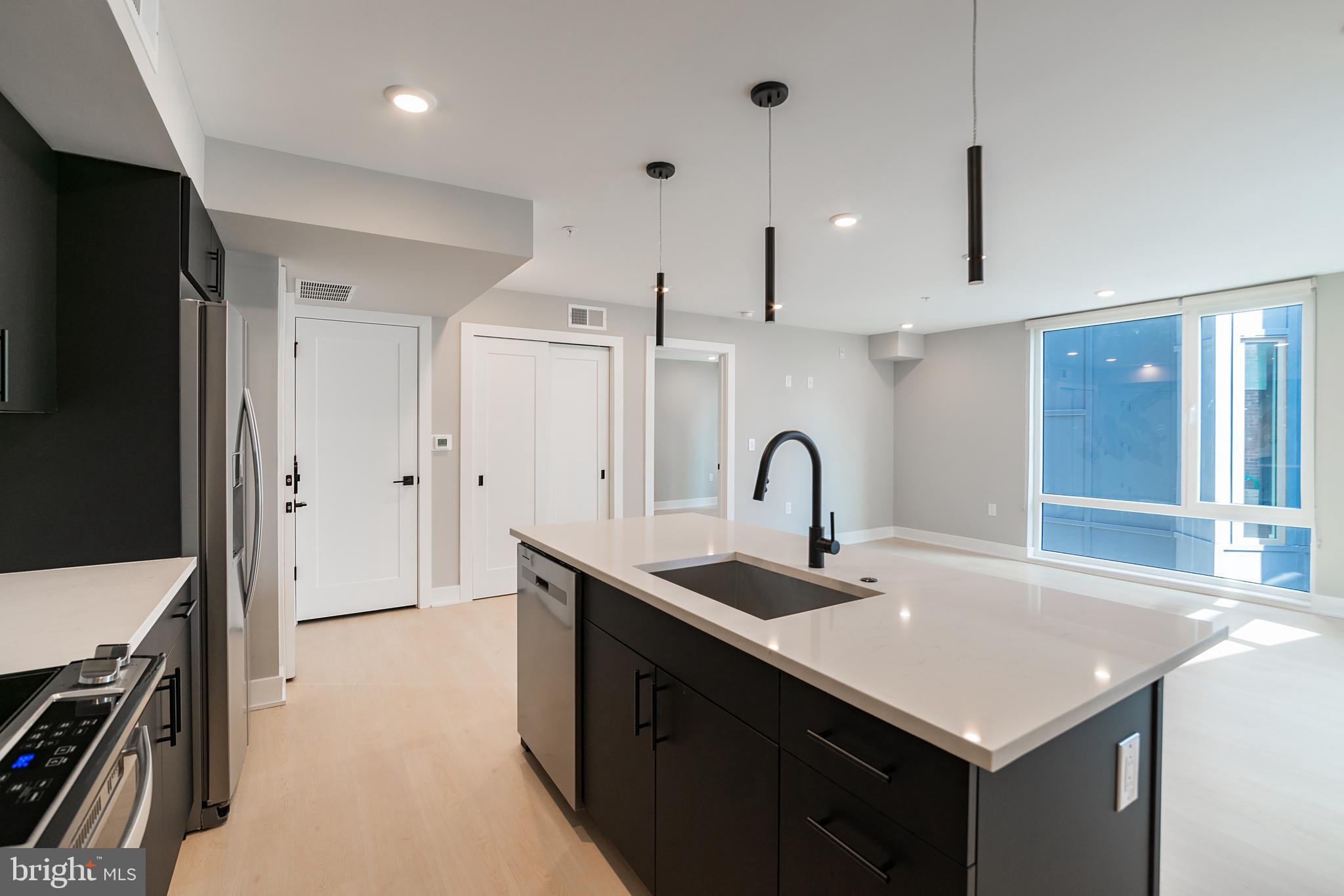6604 Ridge Avenue, Unit 401 Philadelphia, PA 19128 - Photo 6 of 11 a kitchen with kitchen island a sink stainless steel appliances and cabinets