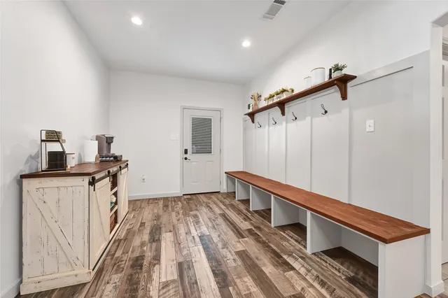 a hallway with a white cabinets a sink and wooden floor
