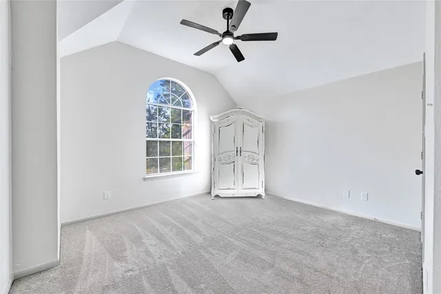 an empty room with chandelier fan and windows