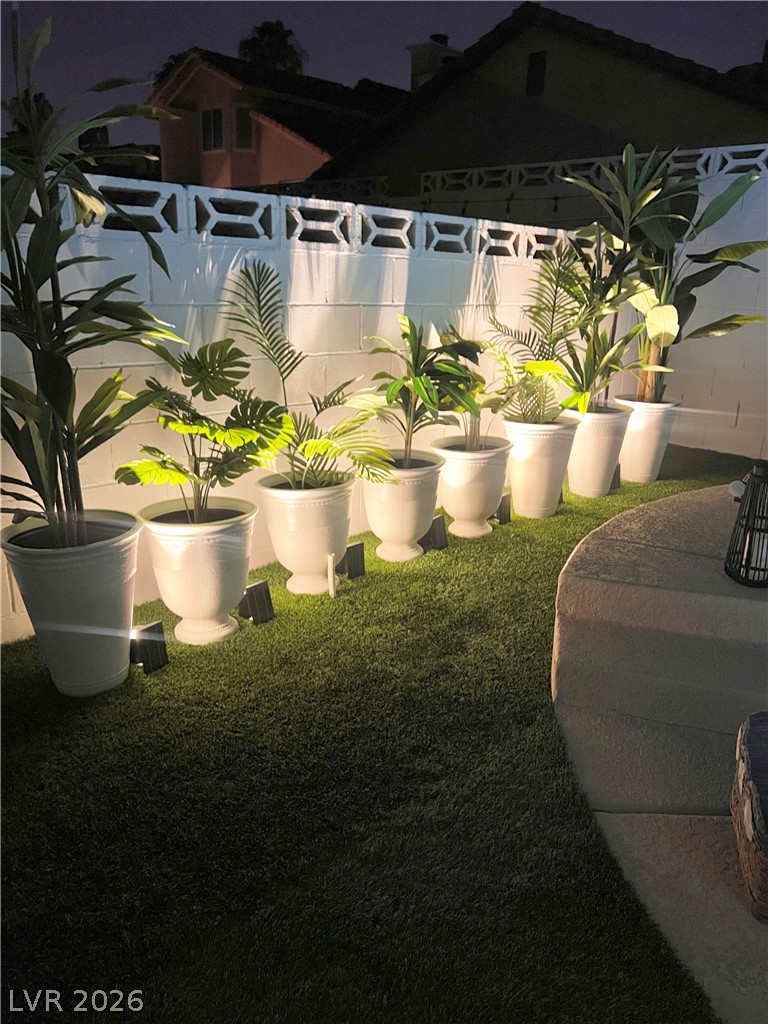 6505 Deadwood Road Las Vegas, NV 89108 - Photo 30 of 33 Illuminated planters line a tidy artificial turf area, offering serene evening ambiance.