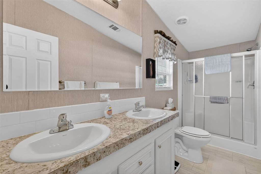 11523 Marvell Way Leesburg, FL 34788 - Photo 17 of 40 a bathroom with a granite countertop sink toilet a large mirror and shower