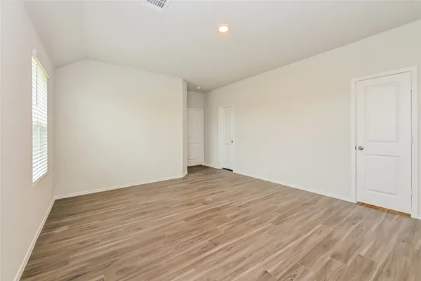 a view of empty room with wooden floor and fan