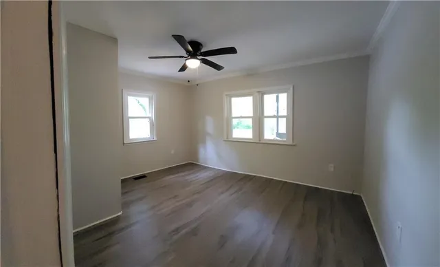 a view of an empty room with a window and wooden floor