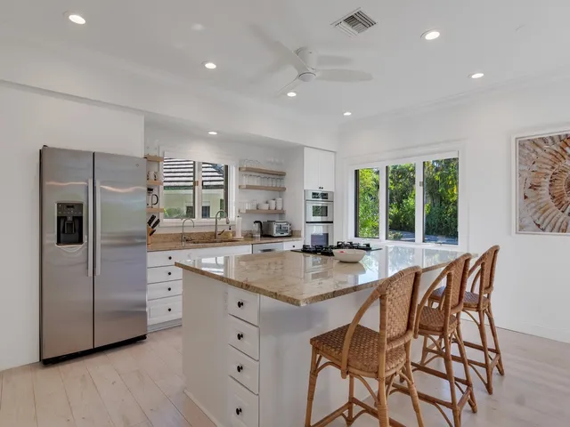 a kitchen with stainless steel appliances granite countertop a sink a stove a refrigerator and island with wooden floor