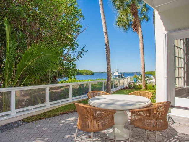 a view of a patio with table and chairs potted plants with wooden floor and fence