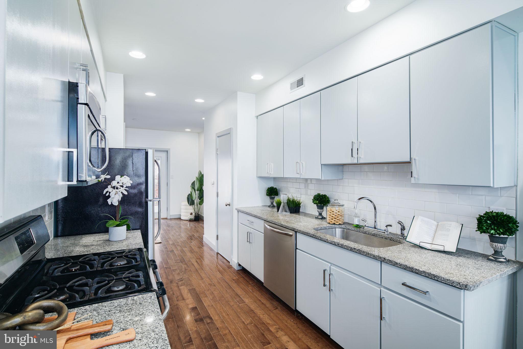 1235 North Taney Street Philadelphia, PA 19121 - Photo 5 of 28 a kitchen with white cabinets and appliances