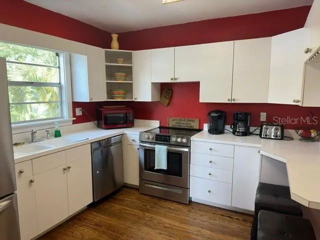 a kitchen with stainless steel appliances a stove a sink cabinets and wooden floor